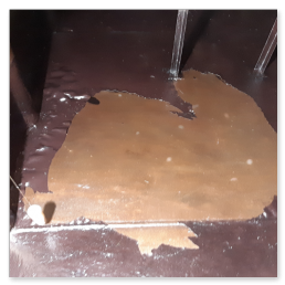 Lose, defekte Innenbeschichtung auf dem Tankboden eines alten kellergeschweißten Heizöltanks aus Stahl